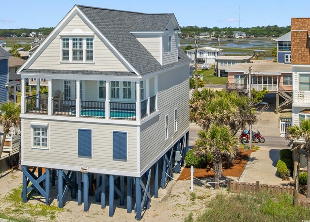 703 S Waccamaw Dr, Garden City Beach, SC 29576 - back of house featuring a shingled roof, a carport, a water view, and fence
