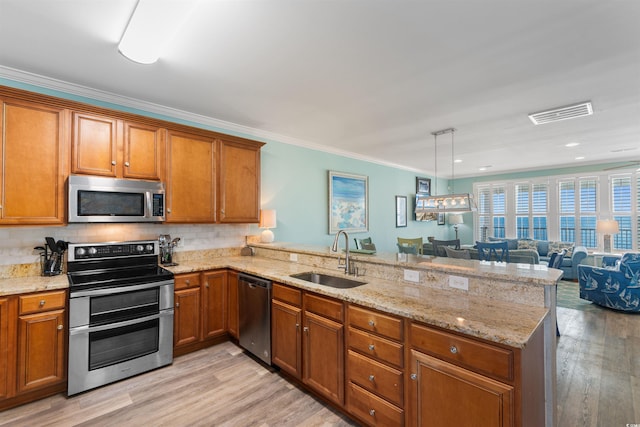 703 S Waccamaw Dr, Garden City Beach, SC 29576 - kitchen featuring stainless steel appliances, a sink, a peninsula, brown cabinetry, and light wood-style floors