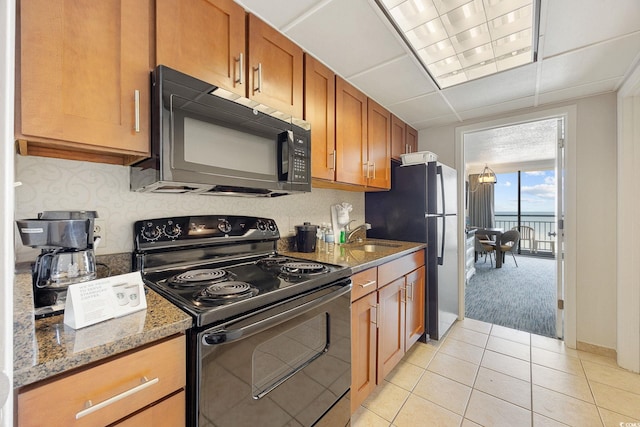1105 S Ocean Blvd Unit 928, Myrtle Beach, SC 29577 - kitchen with black appliances, brown cabinets, light tile patterned flooring, dark stone countertops, and light carpet