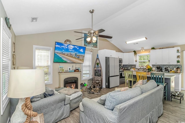 3827 El Duce Pl, Myrtle Beach, SC 29588 - living area with light wood-style floors, a ceiling fan, a lit fireplace, and high vaulted ceiling