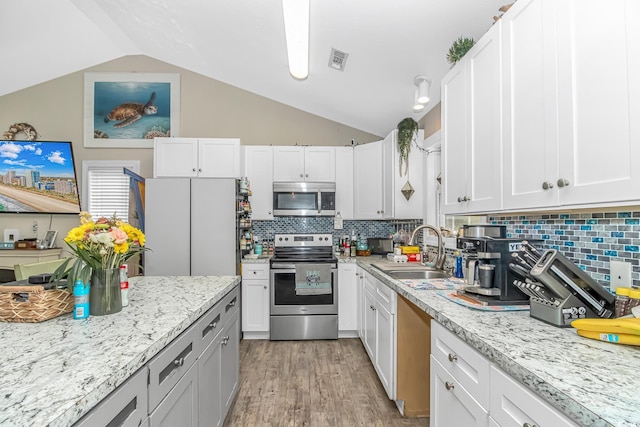 3827 El Duce Pl, Myrtle Beach, SC 29588 - kitchen with stainless steel appliances, a sink, vaulted ceiling, light wood-style flooring, and tasteful backsplash