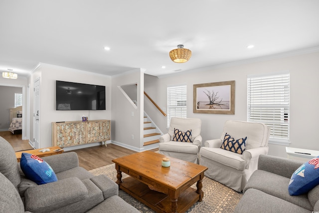 living area with wood finished floors, crown molding, healthy amount of natural light, stairway, and baseboards