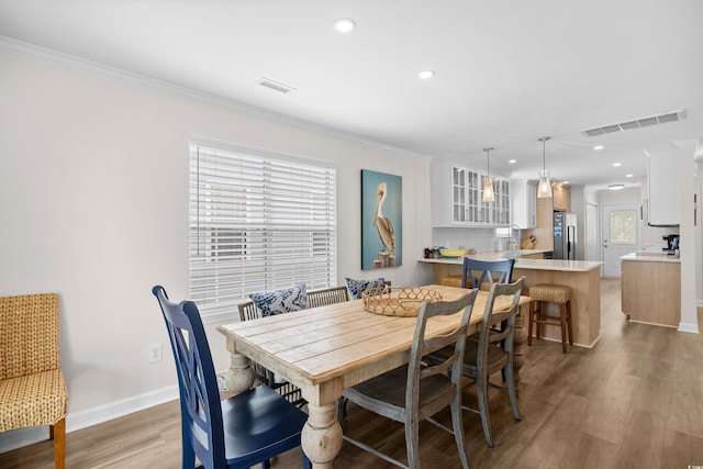 dining room with crown molding, recessed lighting, light wood-style floors, and baseboards