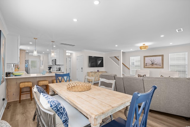 dining room with stairs, light wood-style flooring, recessed lighting, and crown molding