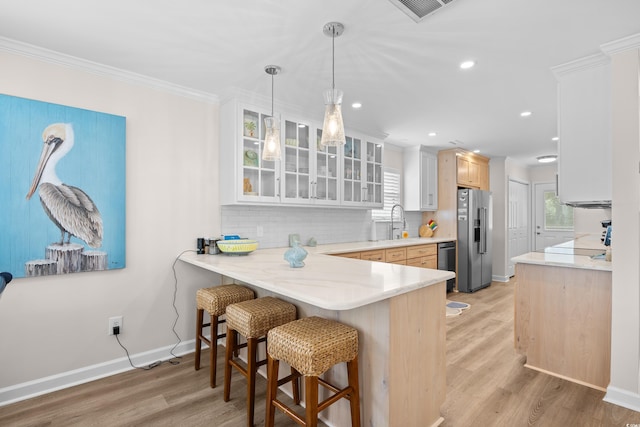 kitchen featuring high end fridge, dishwasher, a kitchen bar, glass insert cabinets, and backsplash