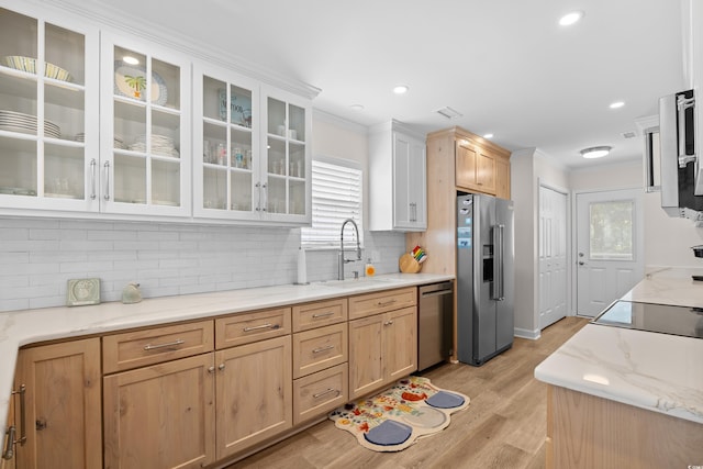 kitchen with appliances with stainless steel finishes, a sink, crown molding, decorative backsplash, and light wood-type flooring