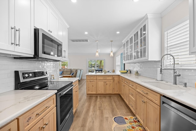 kitchen with appliances with stainless steel finishes, a sink, recessed lighting, light wood-style flooring, and a peninsula
