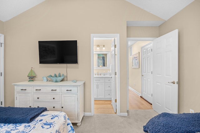bedroom with vaulted ceiling, light carpet, connected bathroom, and baseboards