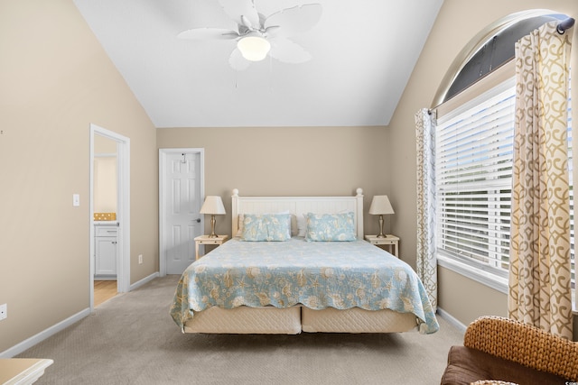 bedroom featuring light colored carpet, vaulted ceiling, multiple windows, baseboards, and ensuite bathroom