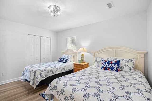 bedroom with wood finished floors, a closet, and baseboards