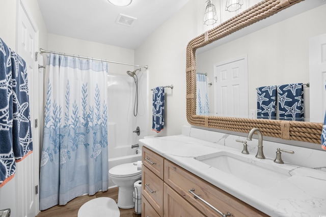 bathroom with wood finished floors, toilet, vanity, and shower / tub combo