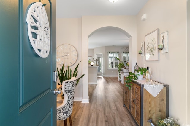 foyer entrance with arched walkways, wood finished floors, and baseboards