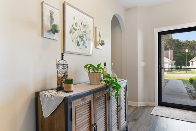 entryway featuring wood finished floors, arched walkways, and baseboards