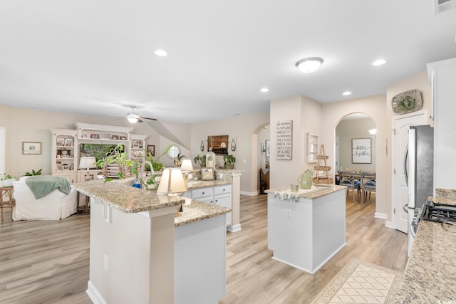 kitchen featuring a spacious island, arched walkways, ceiling fan, light wood-style flooring, and recessed lighting