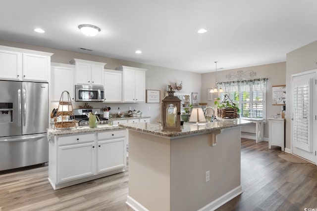 kitchen with appliances with stainless steel finishes, an island with sink, light wood-type flooring, and recessed lighting
