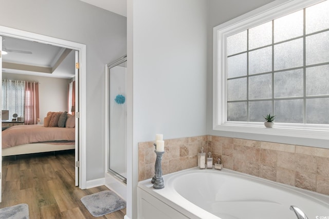 ensuite bathroom featuring a shower stall, a garden tub, and wood finished floors