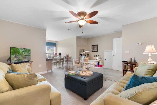 living area with a ceiling fan, light carpet, and baseboards