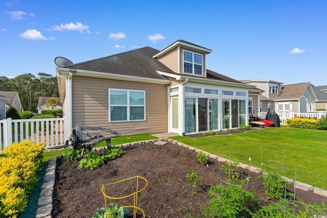 rear view of house with a sunroom, a vegetable garden, and roof with shingles