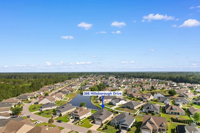 view of property location with nearby suburban area, a large body of water, and a heavily wooded area