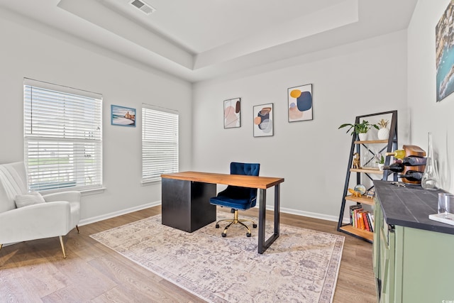 office area with a raised ceiling, wood finished floors, and baseboards