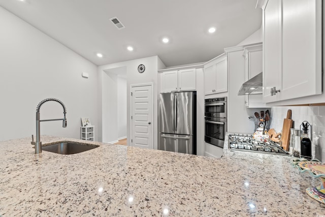 kitchen with appliances with stainless steel finishes, exhaust hood, a sink, light stone counters, and recessed lighting
