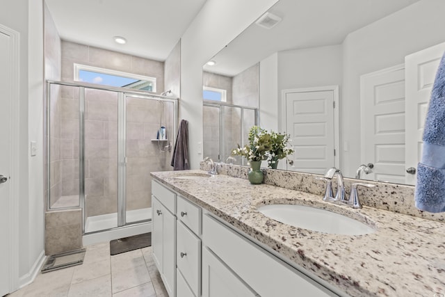 bathroom with a stall shower, healthy amount of natural light, double vanity, and tile patterned floors
