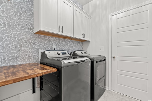 laundry room with washer and dryer, cabinet space, and wallpapered walls