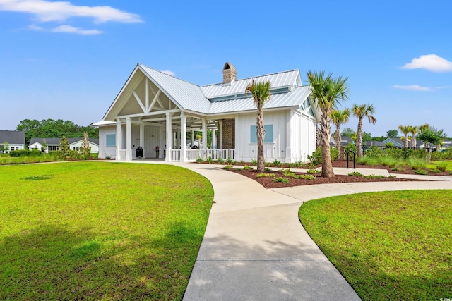 modern farmhouse style home with board and batten siding, a chimney, covered porch, and a front yard
