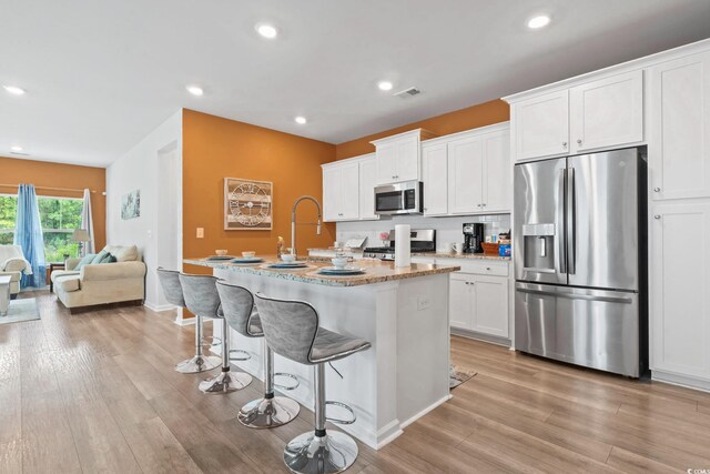 3021 Sistine St, Myrtle Beach, SC 29579 - kitchen featuring appliances with stainless steel finishes, a center island with sink, white cabinets, a breakfast bar area, and recessed lighting