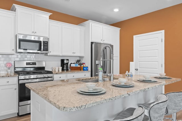 3021 Sistine St, Myrtle Beach, SC 29579 - kitchen with stainless steel appliances, white cabinets, a kitchen island with sink, and a kitchen breakfast bar