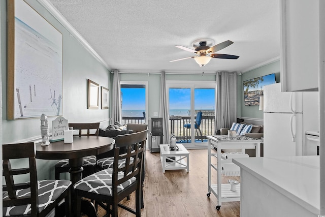 6000 N Ocean Blvd Unit 119, North Myrtle Beach, SC 29582 - dining space featuring crown molding, a ceiling fan, light wood-type flooring, a textured ceiling, and a water view