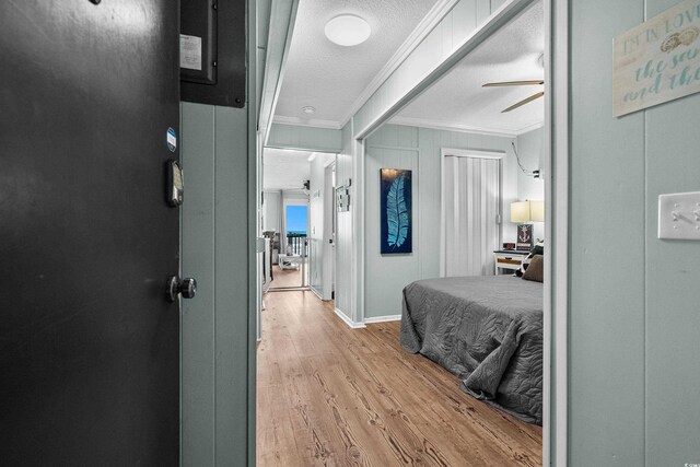 6000 N Ocean Blvd Unit 119, North Myrtle Beach, SC 29582 - bedroom featuring crown molding, light wood-style flooring, a textured ceiling, ceiling fan, and baseboards