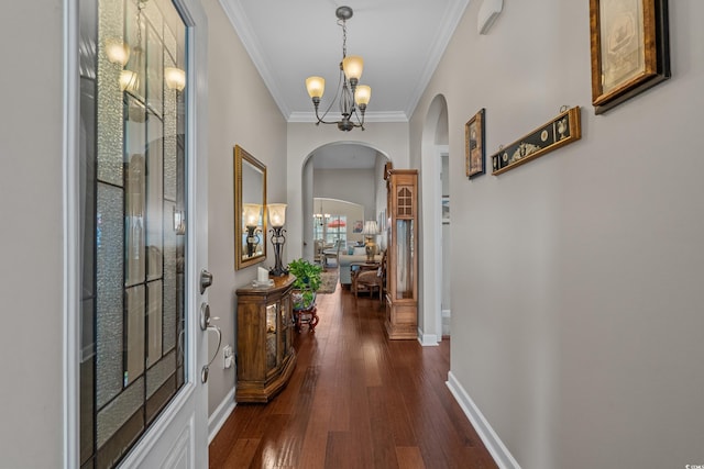 foyer featuring arched walkways, crown molding, dark wood finished floors, baseboards, and a chandelier