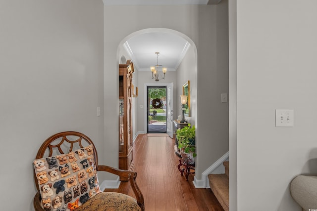 entrance foyer with arched walkways, ornamental molding, wood-type flooring, baseboards, and stairway