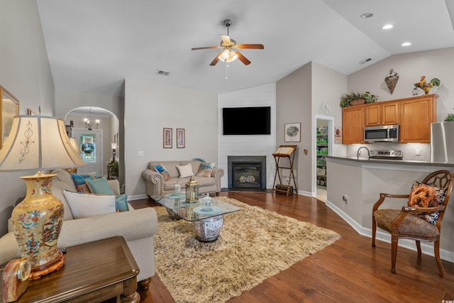 living area featuring ceiling fan, dark wood finished floors, arched walkways, high vaulted ceiling, and a fireplace with flush hearth