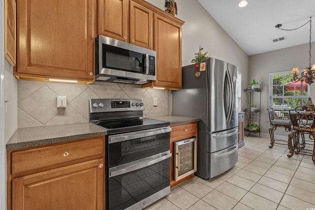 kitchen with stainless steel appliances, lofted ceiling, light tile patterned floors, brown cabinets, and backsplash