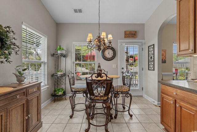 dining area with a chandelier, arched walkways, healthy amount of natural light, and light tile patterned floors