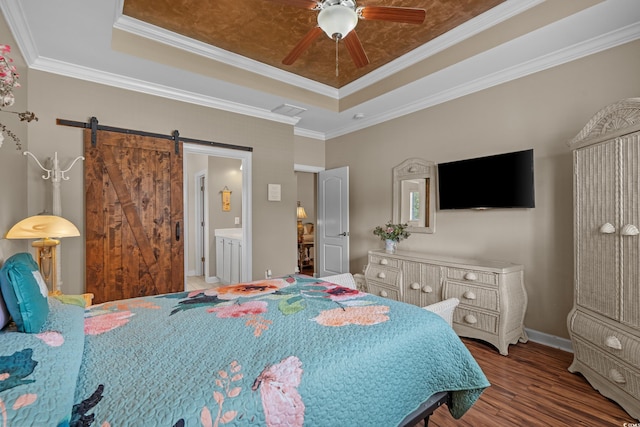 bedroom featuring a tray ceiling, wood finished floors, a barn door, baseboards, and ceiling fan