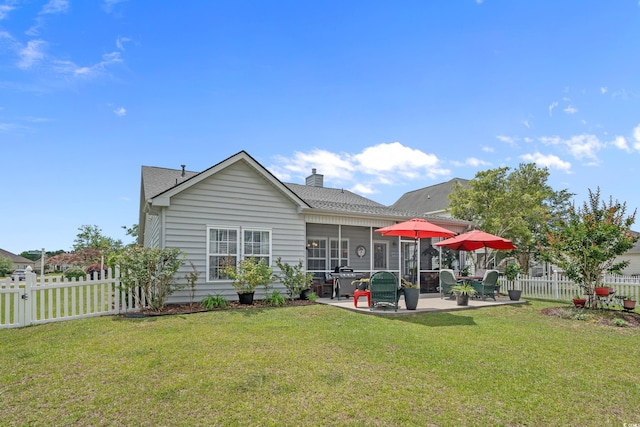 back of house with a patio, a sunroom, a chimney, and roof with shingles