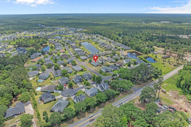 view of property location featuring a heavily wooded area, a large body of water, and nearby suburban area