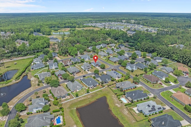 aerial view of property's location with a forest, a large body of water, and nearby suburban area