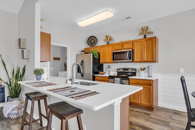 1451 Virginia Pine Dr, Longs, SC 29568 - kitchen featuring appliances with stainless steel finishes, wood finished floors, a kitchen bar, light countertops, and a sink