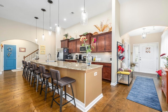 605 Ginger Lily Way, Little River, SC 29566 - kitchen featuring stainless steel appliances, arched walkways, a sink, dark wood-type flooring, and a towering ceiling