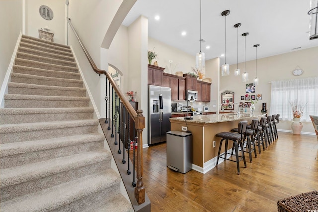605 Ginger Lily Way, Little River, SC 29566 - kitchen featuring stainless steel appliances, light wood-style floors, a kitchen bar, a towering ceiling, and arched walkways