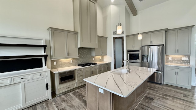 kitchen featuring stainless steel appliances, a sink, gray cabinetry, high vaulted ceiling, and light stone countertops