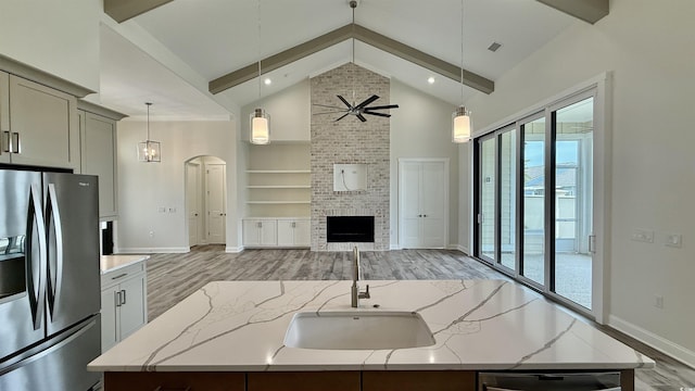 kitchen with stainless steel fridge with ice dispenser, a sink, light wood-type flooring, open floor plan, and high vaulted ceiling