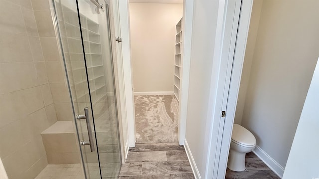full bath with a stall shower, toilet, and baseboards