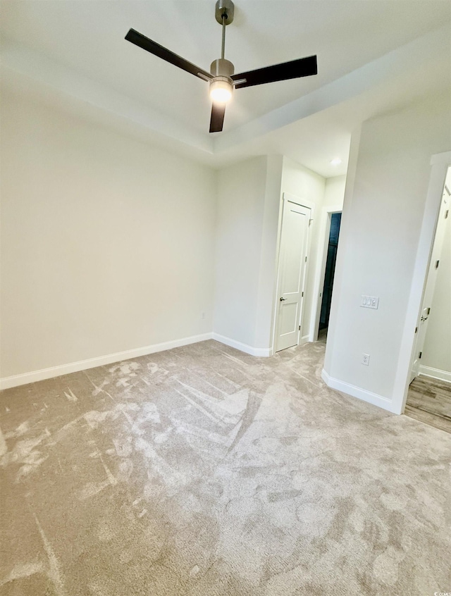 empty room featuring a ceiling fan, carpet floors, and baseboards