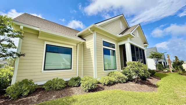 view of property exterior featuring a lawn and a shingled roof