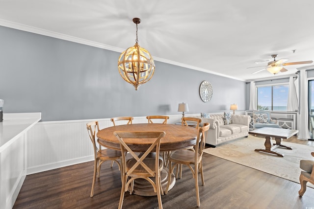 dining space with wood finished floors, crown molding, a chandelier, wainscoting, and ceiling fan